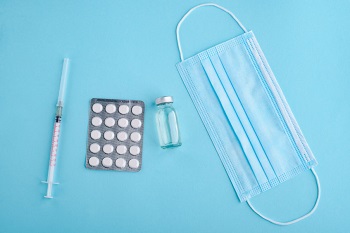 Syringe, pills, and face mask on a blue background