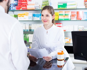 Woman pharmacist is recommending prescription medicine for man client in apothecary.