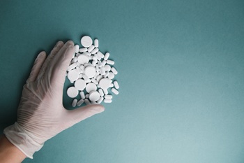 White tablets on a blue background are isolated. Layout of Flatley tablets. Gloved hand with a pill. Virus protection and 2019-ncov.