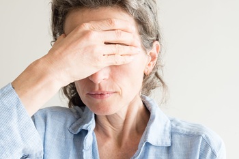 Close up of middle aged woman with hand covering eyes.
