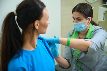 Female medical professional performing vaccination on patient indoors.