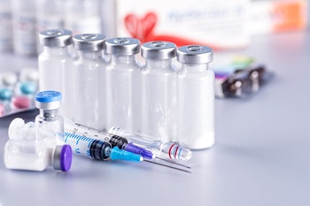 Several clear medical vials with syringes and needle caps on a laboratory surface