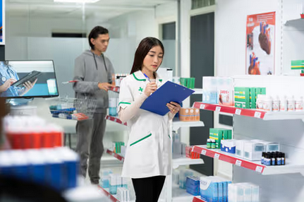 Pharmacy staff member doing inventory next to shopping customer